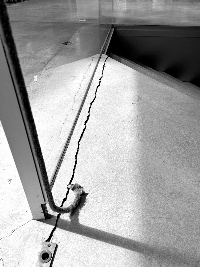 Cracked concrete and broken acoustic seal at sliding door to auditorium.