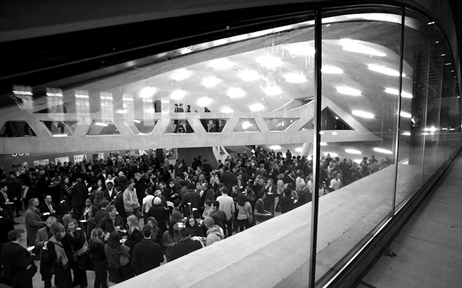 View of Crit Room through eyebrow window looking from University Avenue with wall-to-wall standing people congregating.