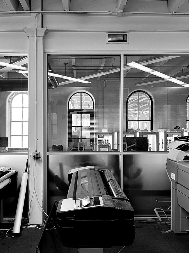 Looking at digital fabrication lab from printer area (corridor) in Sibley Hall, with Milstein Hall visible through fire barrier windows.